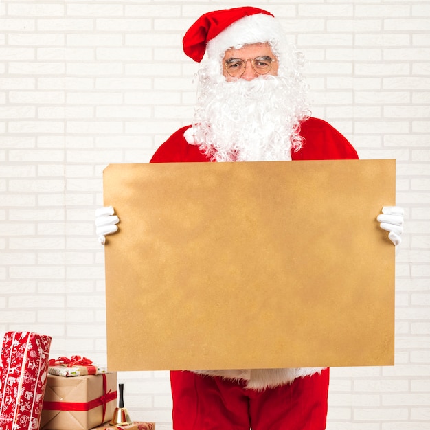 Kostenloses Foto weihnachtsmann, der leeres papier des kraftpapiers hält