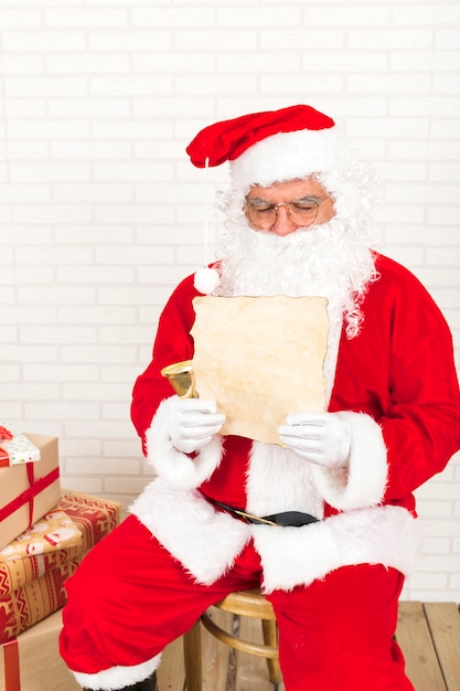 Weihnachtsmann, der Weinlesepapier sitzt und liest