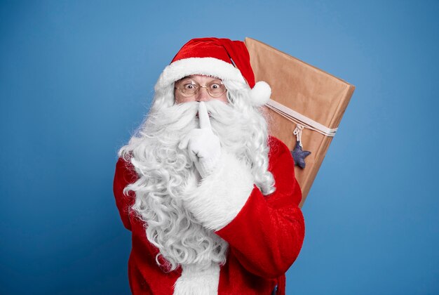 Weihnachtsmann hält Weihnachtsgeschenke hinter seinem Rücken