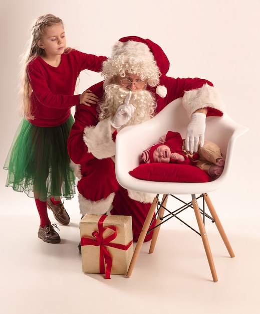 Weihnachtsmann im roten Kostüm mit einem kleinen Mädchen und einem Baby lokalisiert auf Weiß