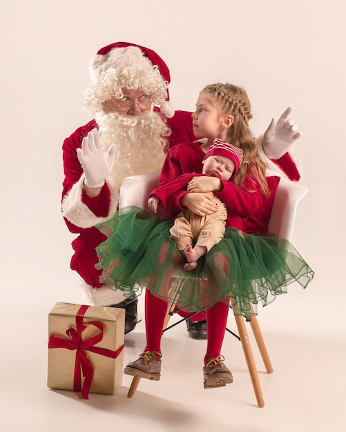 Weihnachtsmann im roten Kostüm mit einem kleinen Mädchen und einem Baby lokalisiert auf Weiß