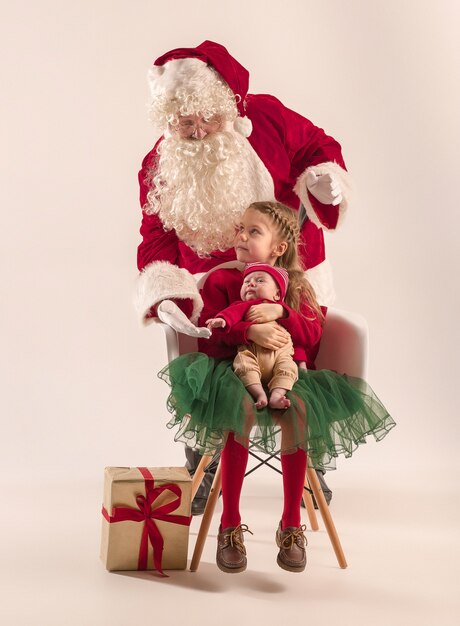 Weihnachtsmann im roten Kostüm mit einem kleinen Mädchen und einem Baby lokalisiert auf Weiß