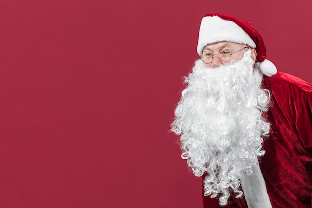 Weihnachtsmann in den Gläsern lugend, schauend auf rotem Hintergrund