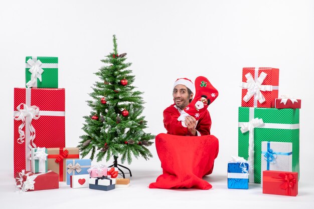 Weihnachtsmann sitzt mit Geschenkboxen und Baum