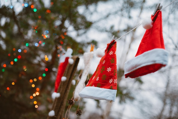 Weihnachtsmannmützen hängen an einer wäscheleine im wald dagegen