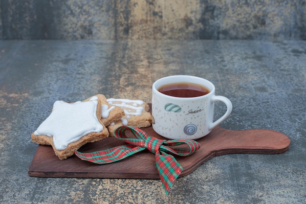 Kostenloses Foto weihnachtsplätzchen mit tasse tee auf holzbrett