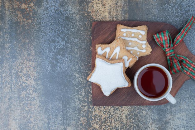 Weihnachtsplätzchen mit Tasse Tee auf Holzbrett