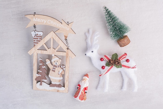 Weihnachtsschmuck, Spielzeughirsche, Kiefer und Santa auf weißer Oberfläche.
