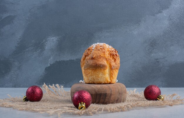 Weihnachtsschmuck und ein Cupcake auf einem Stück Stoff auf Marmoroberfläche