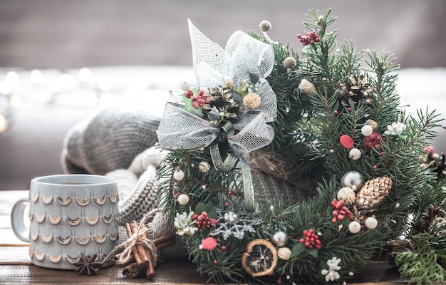 Weihnachtsstillleben von Weihnachtsbäumen und -dekorationen, festlicher Kranz vor dem Hintergrund von gestrickten Kleidern und schönen Tassen, Weihnachtsgewürze