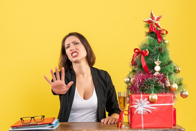 Weihnachtsstimmung mit der jungen unzufriedenen ernsthaften wütenden emotionalen Geschäftsdame, die fünf auf Gelb zeigt