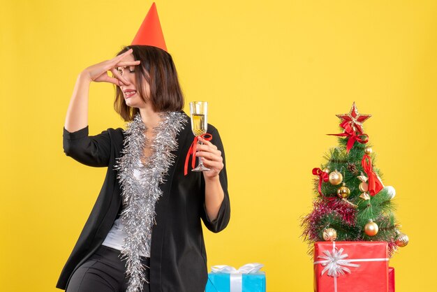 Weihnachtsstimmung mit der schönen Dame des sauren Gesichts, die Wein im Büro auf gelb hält