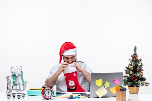 Weihnachtsstimmung mit jungem Erwachsenen mit Weihnachtsmann-Hut und Blick in die Weihnachtssocke im Büro