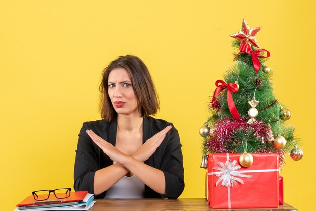 Weihnachtsstimmung mit junger konzentrierter schöner Frau, die Stoppgeste macht und im Büro sitzt