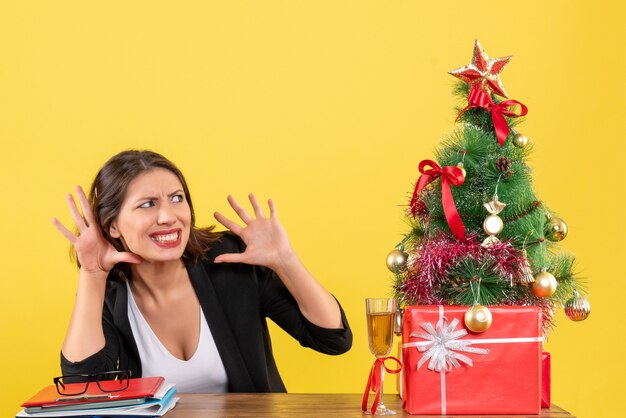 Weihnachtsstimmung mit junger unbefriedigter ernsthafter emotionaler nervöser Geschäftsdame auf Gelb