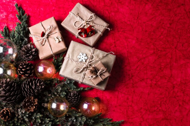 Weihnachtsverzierungen auf rotem Hintergrund mit eingewickelten Geschenken
