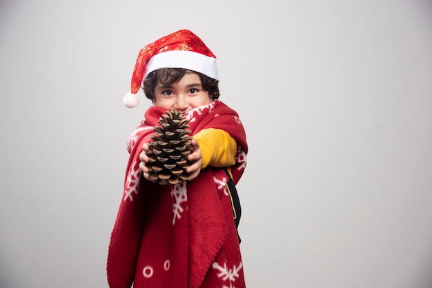 Weihnachtszeit mit kind verkleidet in roter weihnachtsmann-uniform mit tannenzapfen