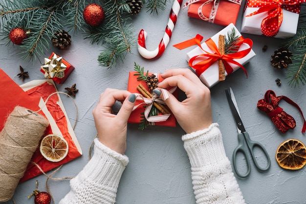 Weihnachtszusammensetzung mit den Händen, die Gegenwart schmücken