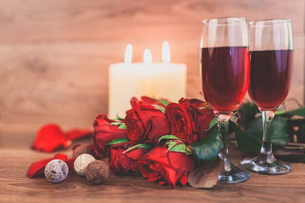 Weingläser mit brennenden Kerzen und ein Strauß Rosen