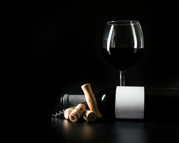 Weinglas und Flasche nahe Korkenzieher und Korken