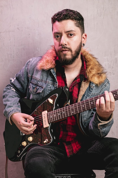 Kostenloses Foto weinlese gekleideter mann, der schöne gitarre spielt