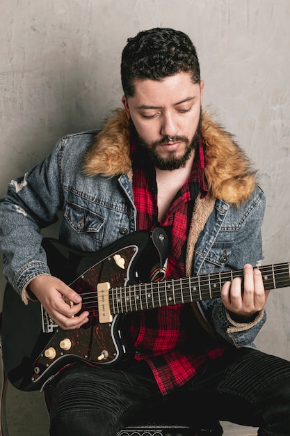 Kostenloses Foto weinlese gekleideter rocker, der e-gitarre spielt