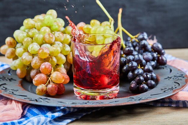 Weintraube und ein Glas Saft auf Schwarz.