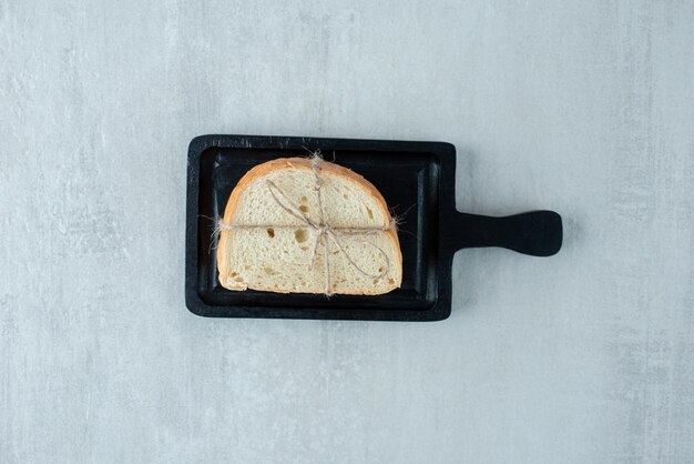 Weißbrot mit Seil auf dunklem Brett gebunden.