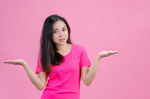 Weiße asiatische Frau, die beide Hände auf einem Rosa trägt.