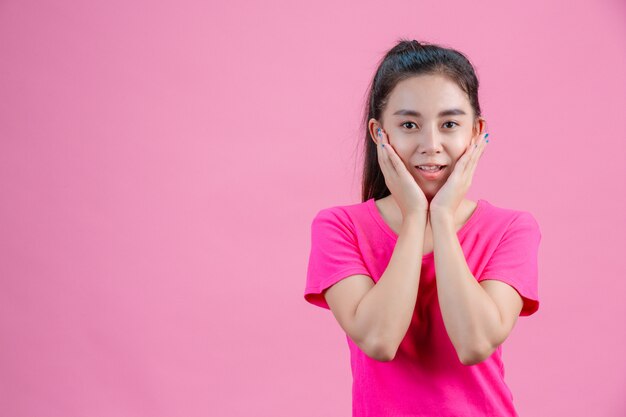 Weiße asiatische Frauen tragen rosa Hemden. Mit beiden Händen das Gesicht auf dem Rosa halten.