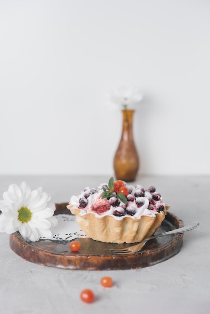 Kostenloses Foto weiße blume und köstliche minitörtchen mit frischen beeren auf hölzernem umhüllungsbehälter