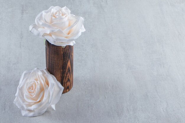 Weiße Blumen in einem Holzkrug auf dem weißen Tisch.
