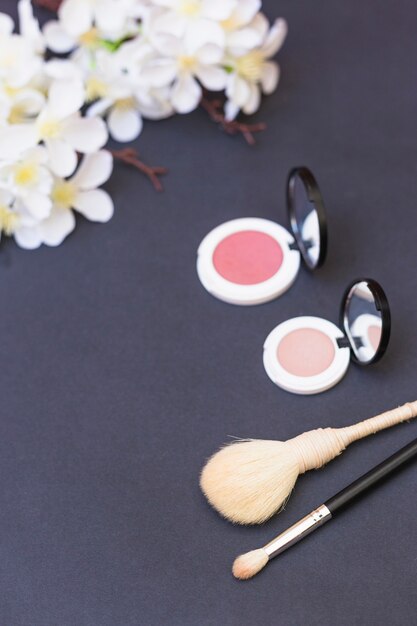 Weiße Blumenstraußblume; Rouge und Make-up Pinsel auf grauem Hintergrund