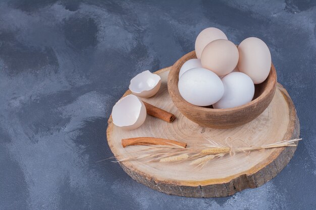 Weiße Eier in einer Holzschale auf einem Holzbrett