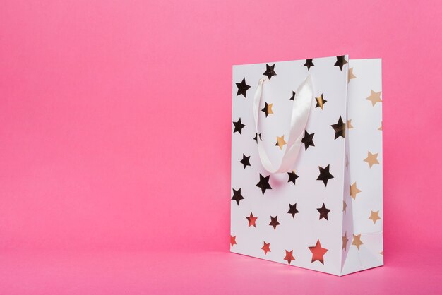 Weiße Einkaufstasche mit Sternformmuster auf rosa Hintergrund