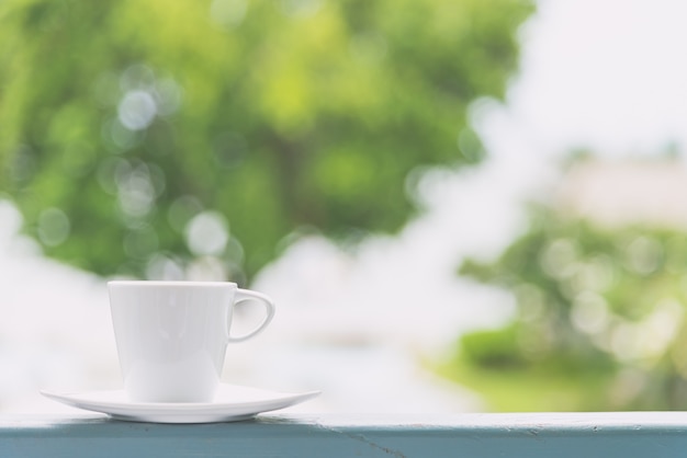 Weiße Kaffeetasse mit Ansichthintergrund im Freien - Weinlesefiltereffekt