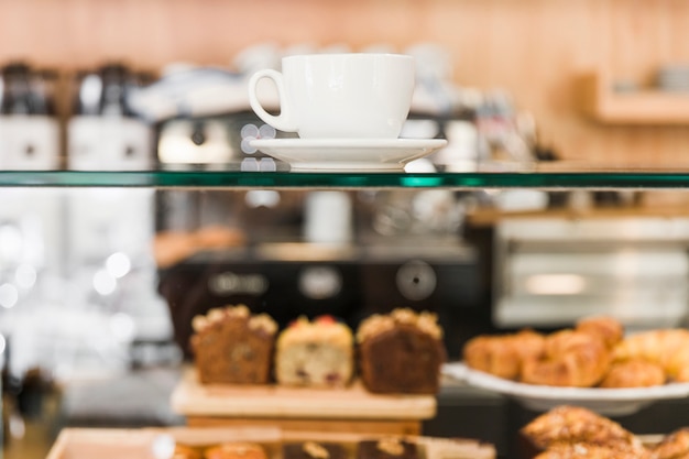 Weiße Kaffeetasse über Glasschrank im Cafégeschäft