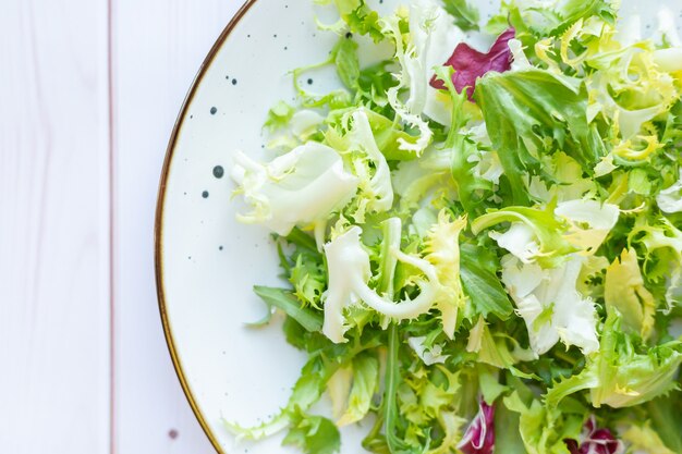 Weiße Keramikplatte mit frischem Salat auf Holzoberfläche