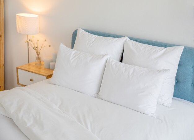 Bequemes blaues kissen auf weißer bettdekoration im schlafzimmer