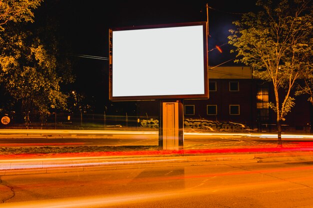 Weiße leere Anschlagtafel mit unscharfen Ampeln auf der Straße