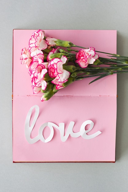 Weiße Liebesaufschrift mit Blumen auf Notizbuch