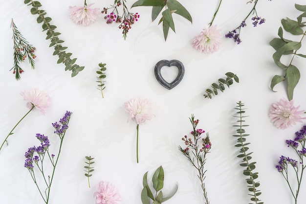 Weiße Oberfläche mit mehreren Blumen und romantische Herz