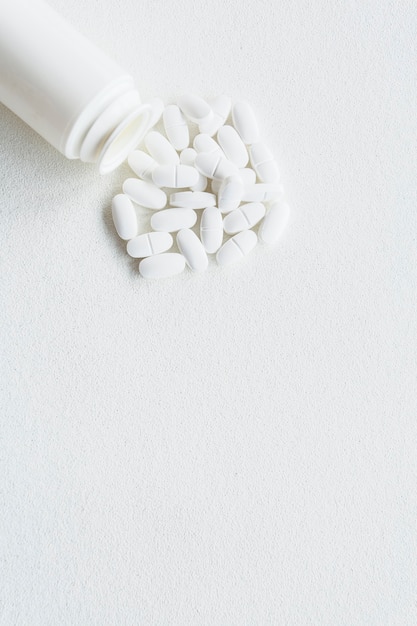 Weiße Pillen und Plastikflasche auf weißem Hintergrund