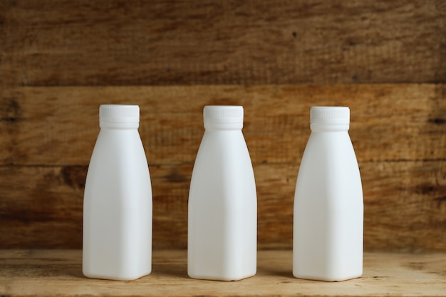 Kostenloses Foto weiße plastikmilchflaschen auf retro holztischhintergrund