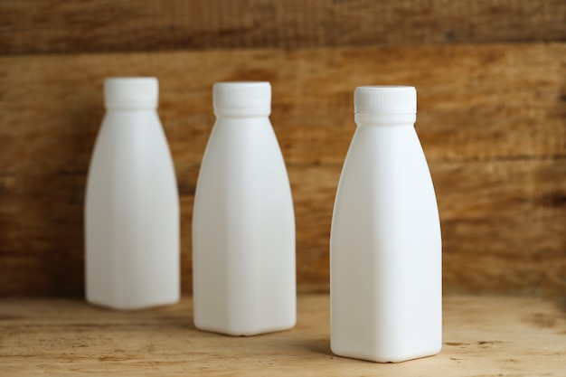 Weiße Plastikmilchflaschen auf Retro Holztischhintergrund