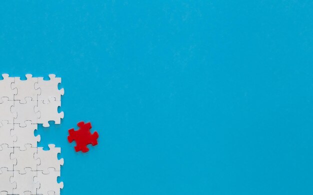 Weiße Puzzles und ein rotes auf blauem Hintergrund liegen flach