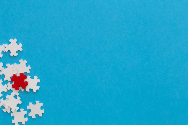 Weiße Puzzles und ein rotes auf blauem Hintergrund liegen flach