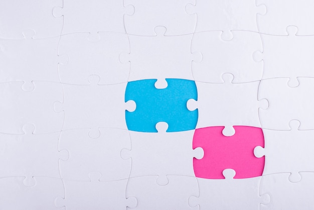 Weiße Puzzleteile und rosa und blauer Hintergrund