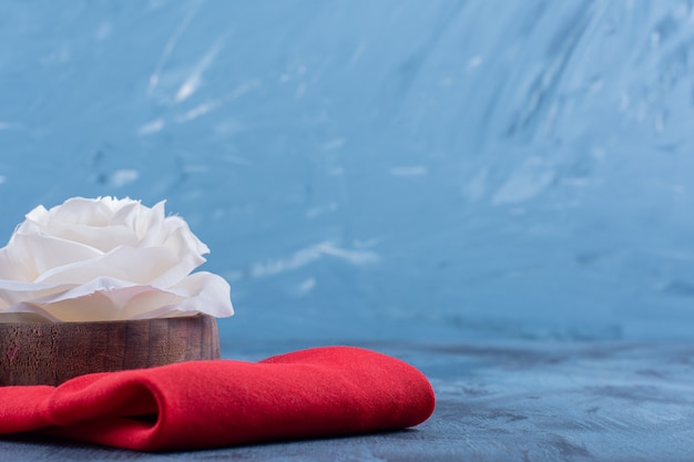 weiße Rosenblüte auf roter Tischdecke auf blauem.