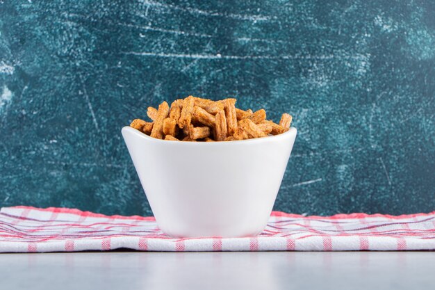 Weiße Schüssel mit knusprigen Stockcrackern auf Stein.